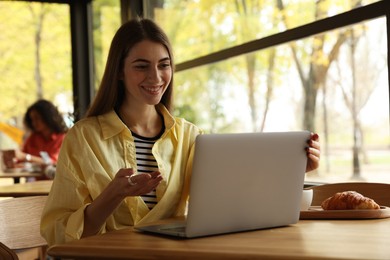 Photo of Woman working on laptop at table in cafe