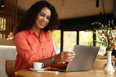 Photo of Woman working on laptop at table in cafe