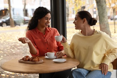 Photo of Happy women with coffee drinks chatting in cafe