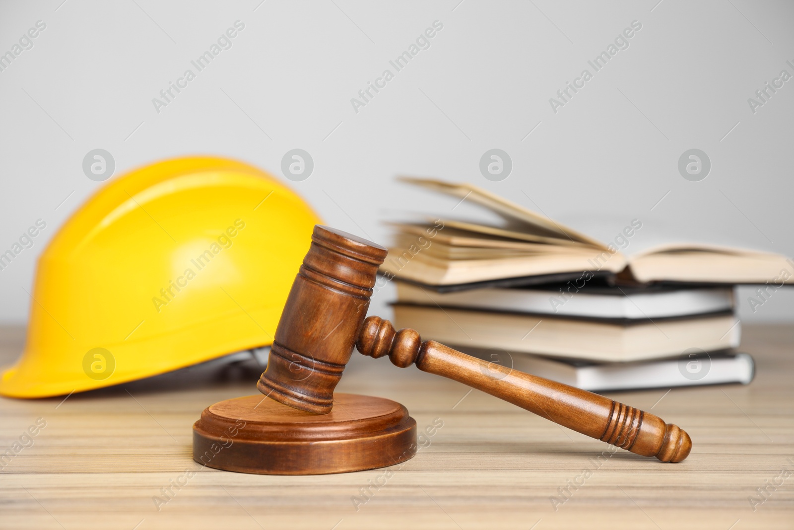 Photo of Accident at work concept. Gavel, books and construction worker's protective gear on wooden table, selective focus