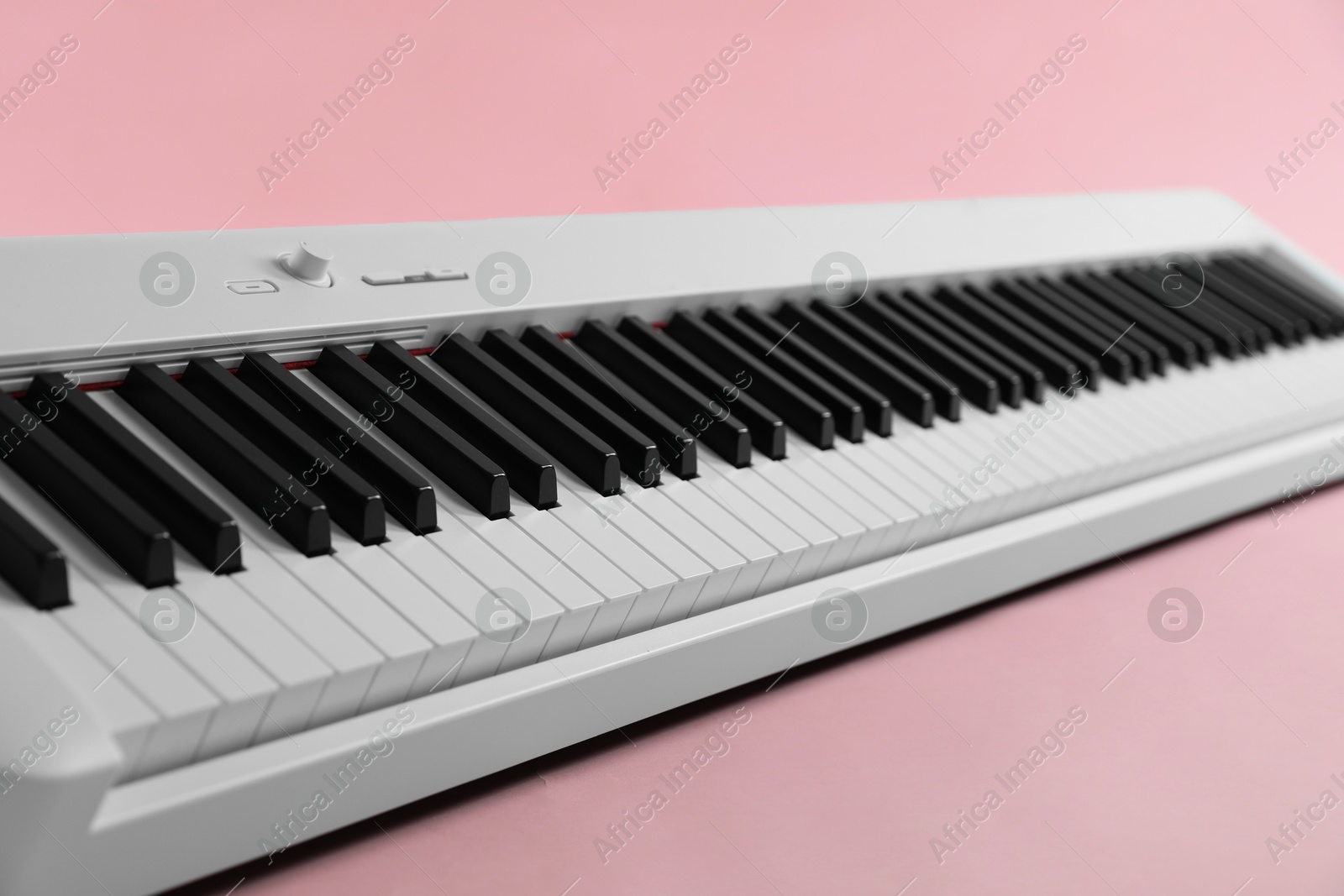 Photo of Synthesizer on pink background, closeup. Electronic musical instrument