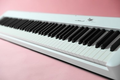 Photo of Synthesizer on pink background, closeup. Electronic musical instrument