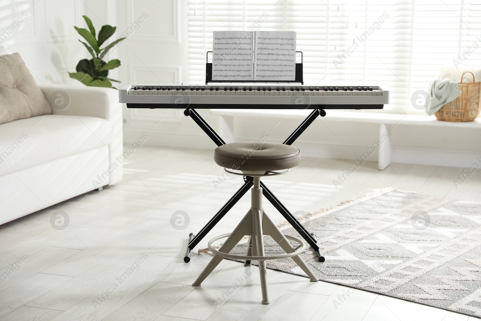 Photo of Synthesizer with music sheets and stool at home