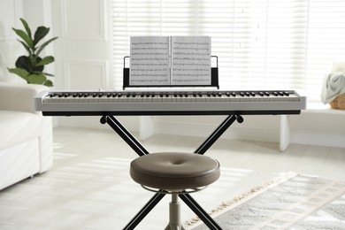 Photo of Synthesizer with music sheets and stool at home