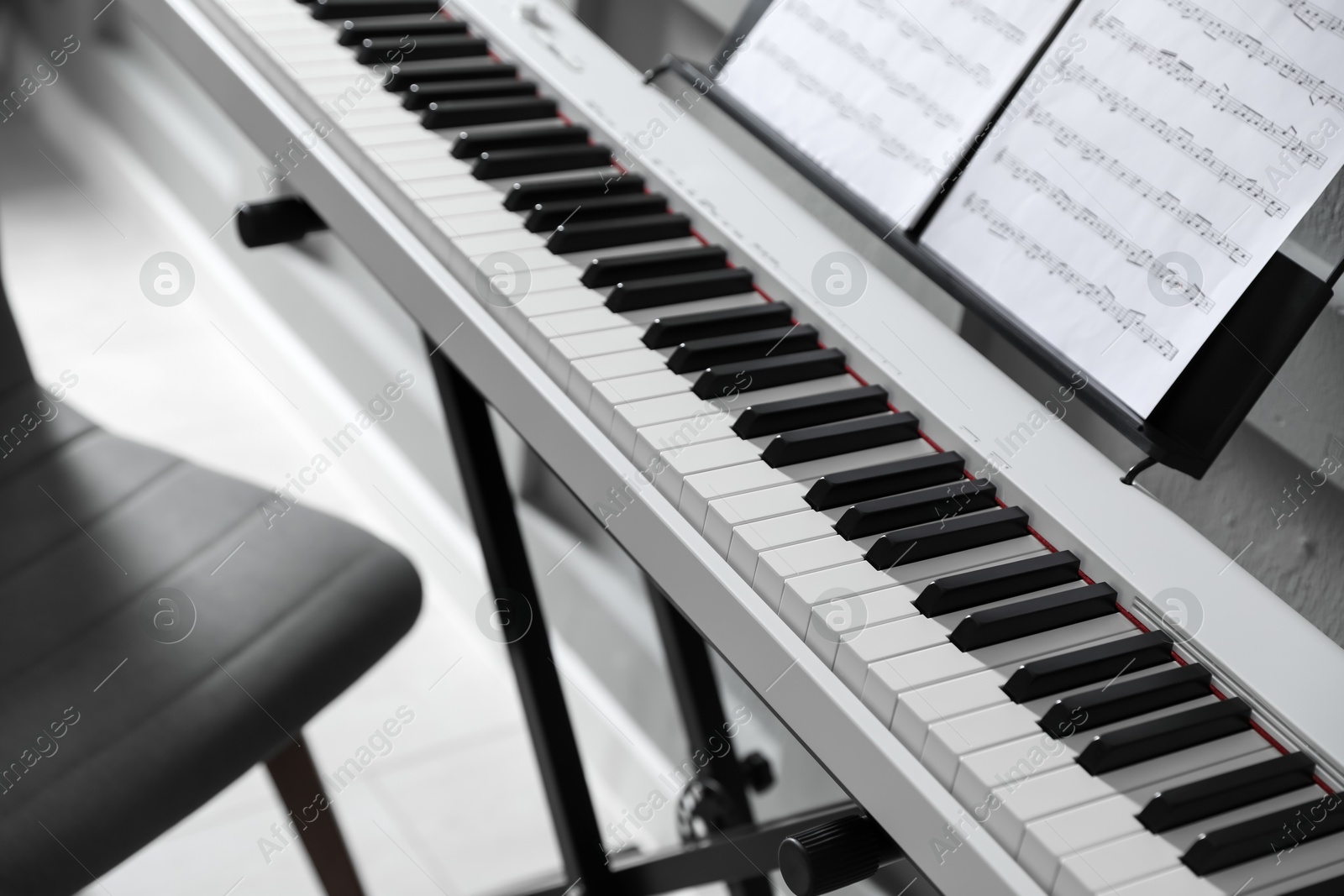 Photo of Synthesizer with music sheets at home, closeup