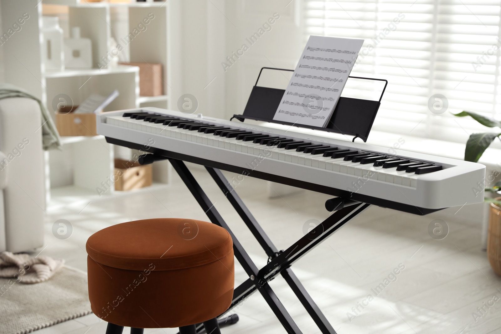 Photo of Synthesizer with music sheet and pouf at home