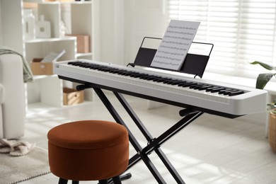 Photo of Synthesizer with music sheet and pouf at home