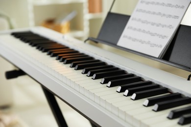 Photo of Synthesizer with music sheet at home, closeup