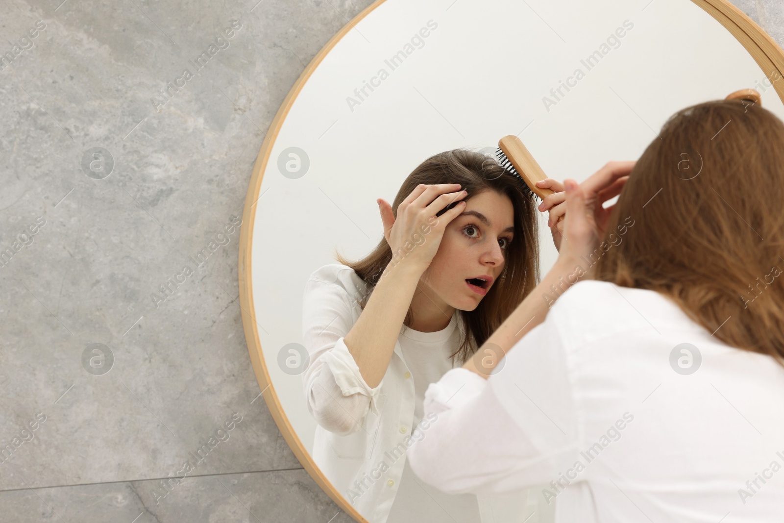 Photo of Girl with hair loss problem near mirror in bathroom, space for text