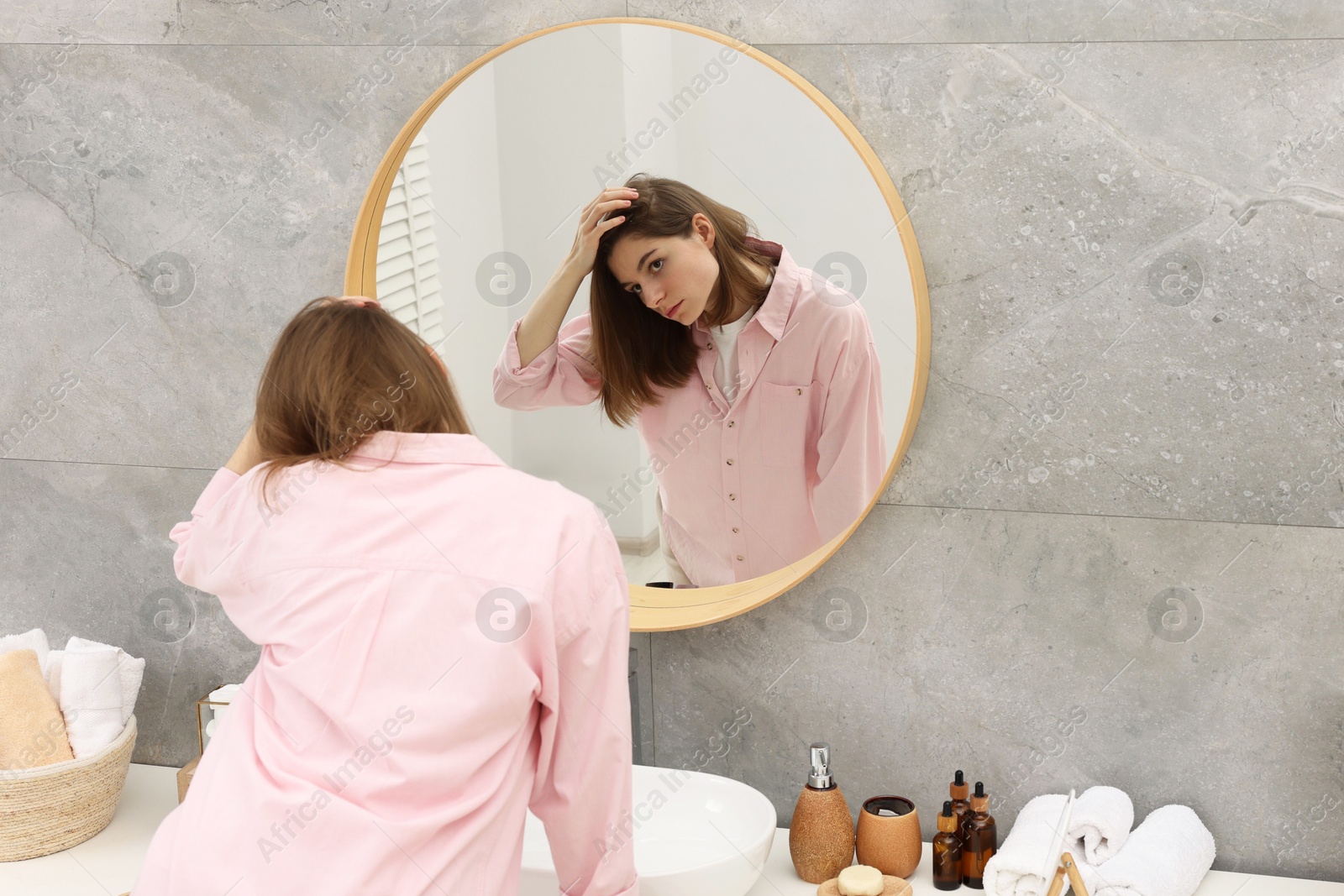 Photo of Girl with hair loss problem near mirror in bathroom