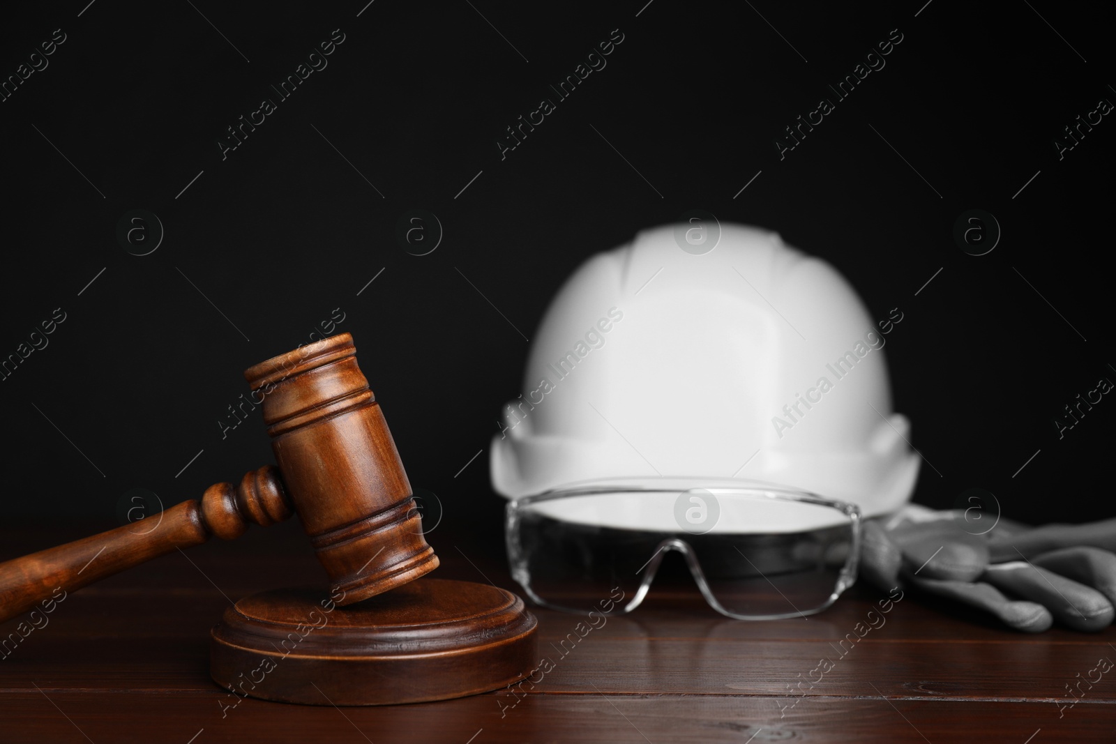 Photo of Accident at work concept. Gavel and construction worker's protective gear on wooden table, selective focus