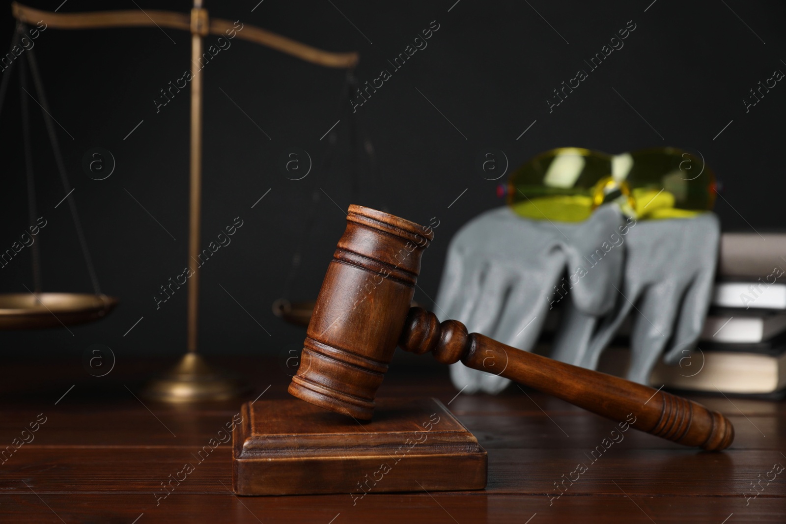 Photo of Accident at work concept. Gavel, books, scales and construction worker's protective gear on wooden table, selective focus