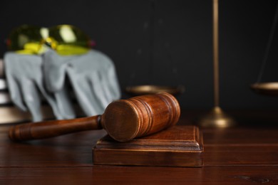 Photo of Accident at work concept. Gavel and construction worker's protective gear on wooden table, selective focus