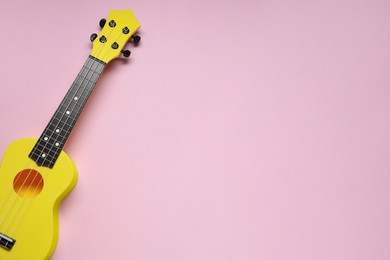 Photo of One ukulele on pink background, top view. Space for text