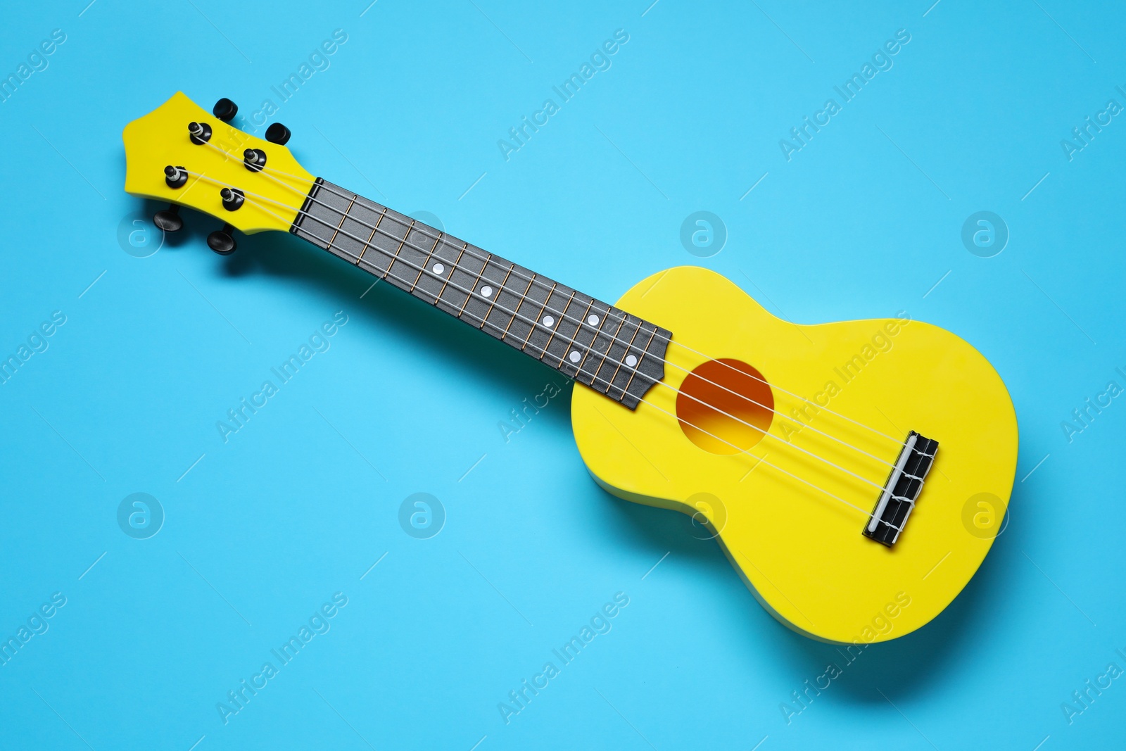 Photo of One ukulele on light blue background, top view