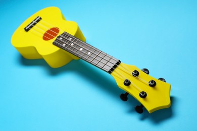 Photo of One ukulele on light blue background, closeup. String musical instrument