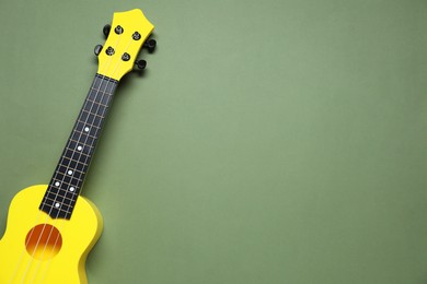 Photo of One ukulele on olive background, top view. Space for text