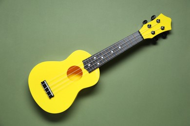 Photo of One ukulele on olive background, top view