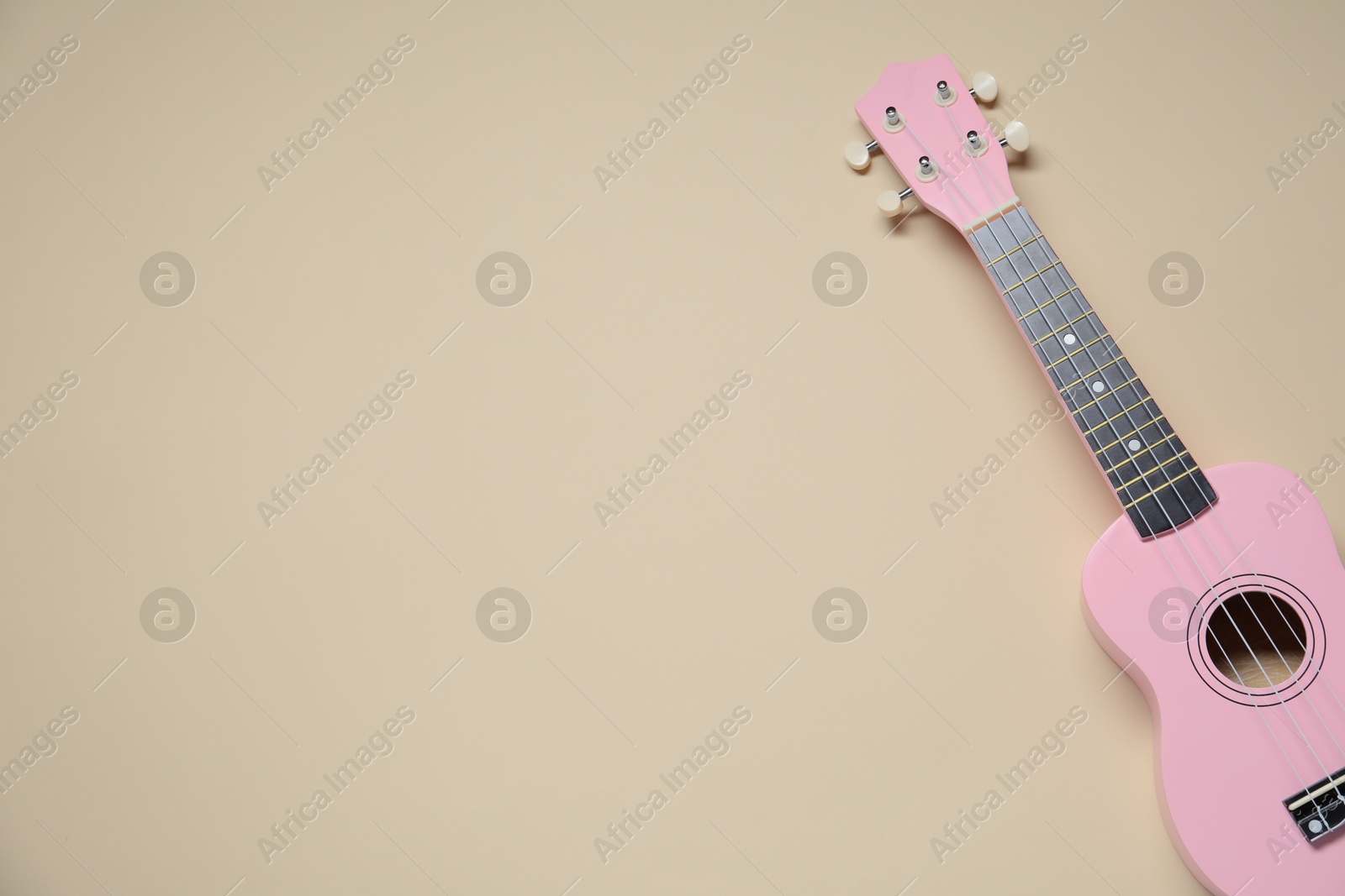 Photo of One ukulele on beige background, top view. Space for text