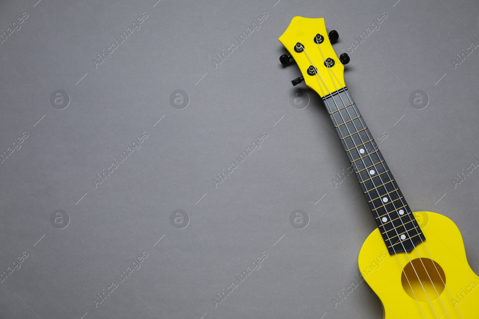 Photo of One ukulele on grey background, top view. Space for text