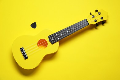 Photo of One ukulele on yellow background, top view