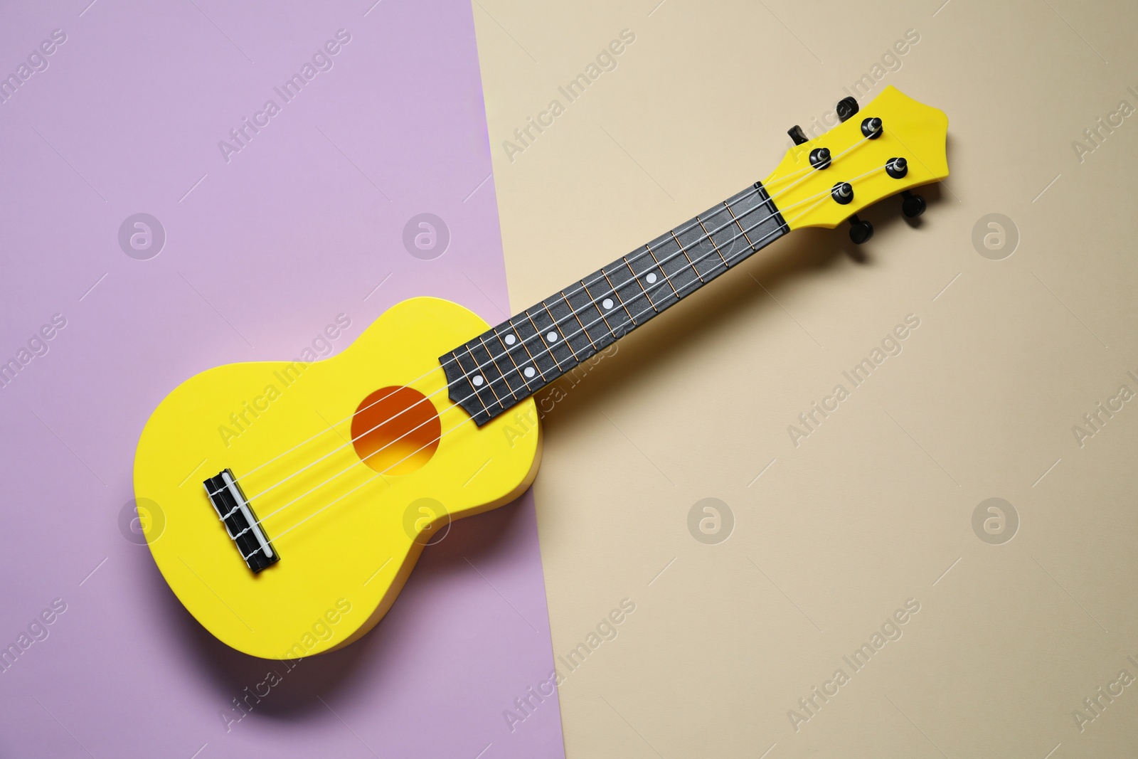 Photo of One ukulele on color background, top view