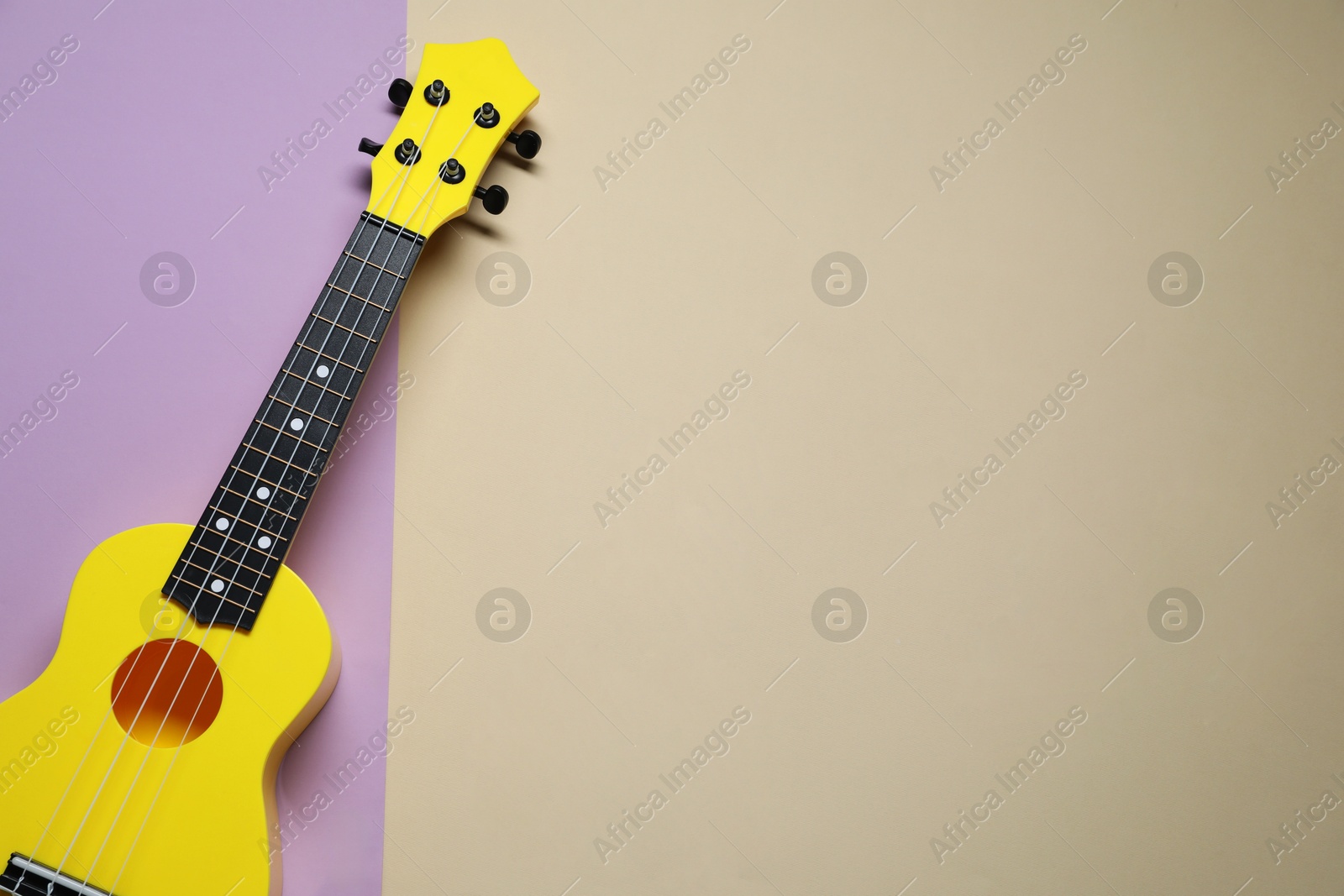 Photo of One ukulele on color background, top view. Space for text