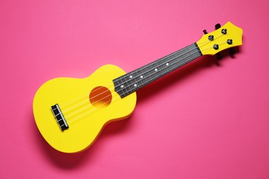 Photo of One ukulele on pink background, top view