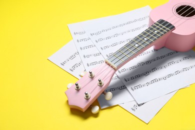 Ukulele and music sheets on yellow background