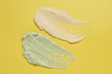 Photo of Samples of different body scrubs on yellow background, top view