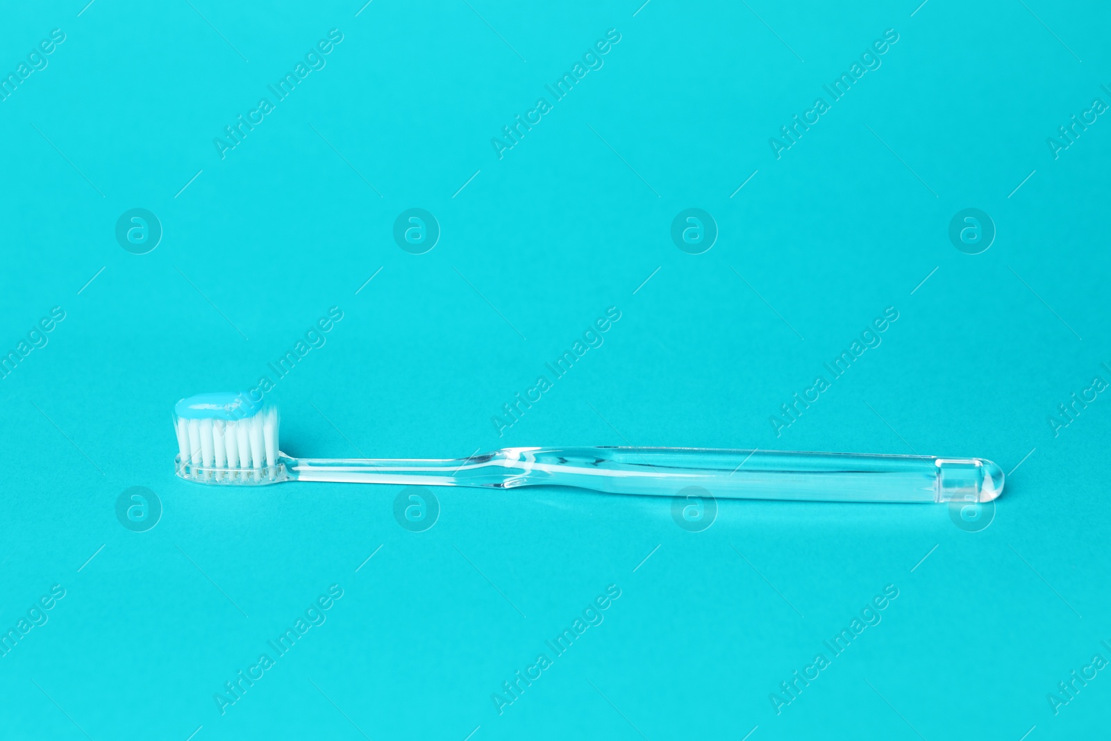 Toothbrush with toothpaste in air on light blue background Photo of Toothbrush with toothpaste in air on light blue background