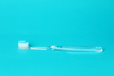 Photo of Toothbrush with toothpaste in air on light blue background