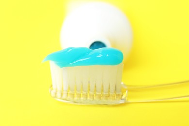 Photo of Toothbrush with toothpaste and tube on yellow background, closeup