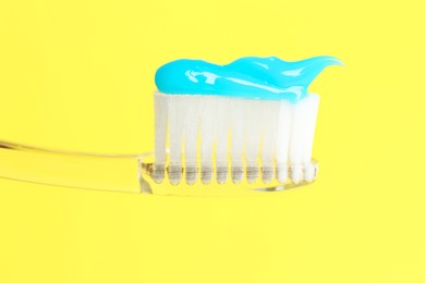 Photo of Toothbrush with toothpaste in air on yellow background, closeup