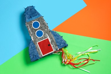 Photo of Bright pinata in shape of spaceship on color background, top view