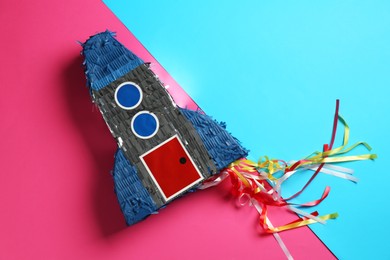 Photo of Bright pinata in shape of spaceship on color background, top view