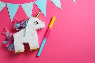 Photo of Bright pinata in shape of unicorn and party accessories on pink background, top view. Space for text