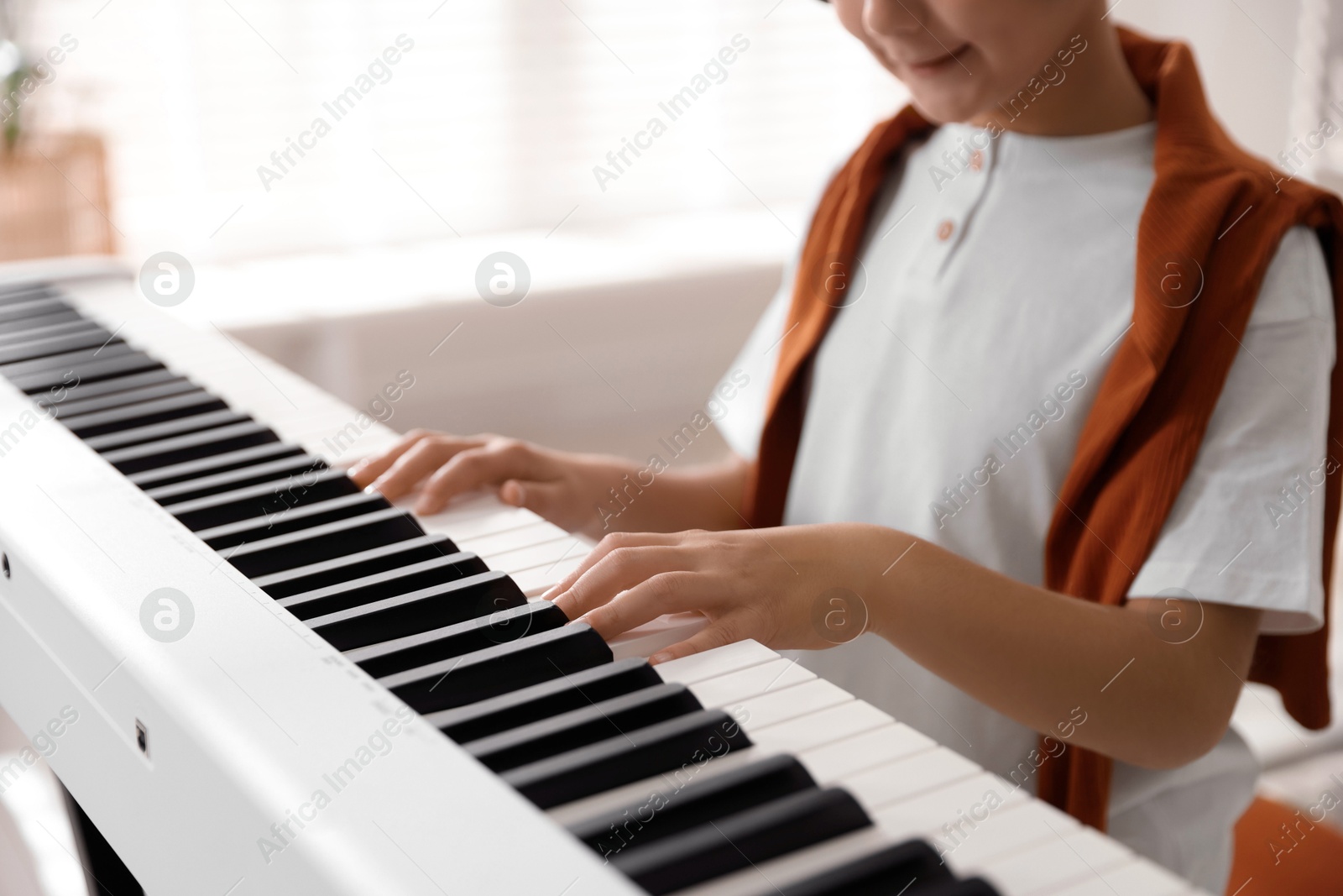 Photo of Boy playing synthesizer at home, closeup. Electronic musical instrument