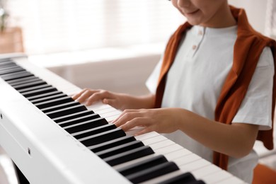 Boy playing synthesizer at home, closeup. Electronic musical instrument