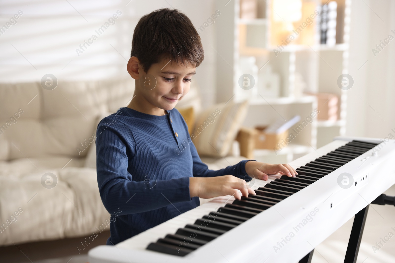 Photo of Cute boy playing synthesizer at home. Electronic musical instrument