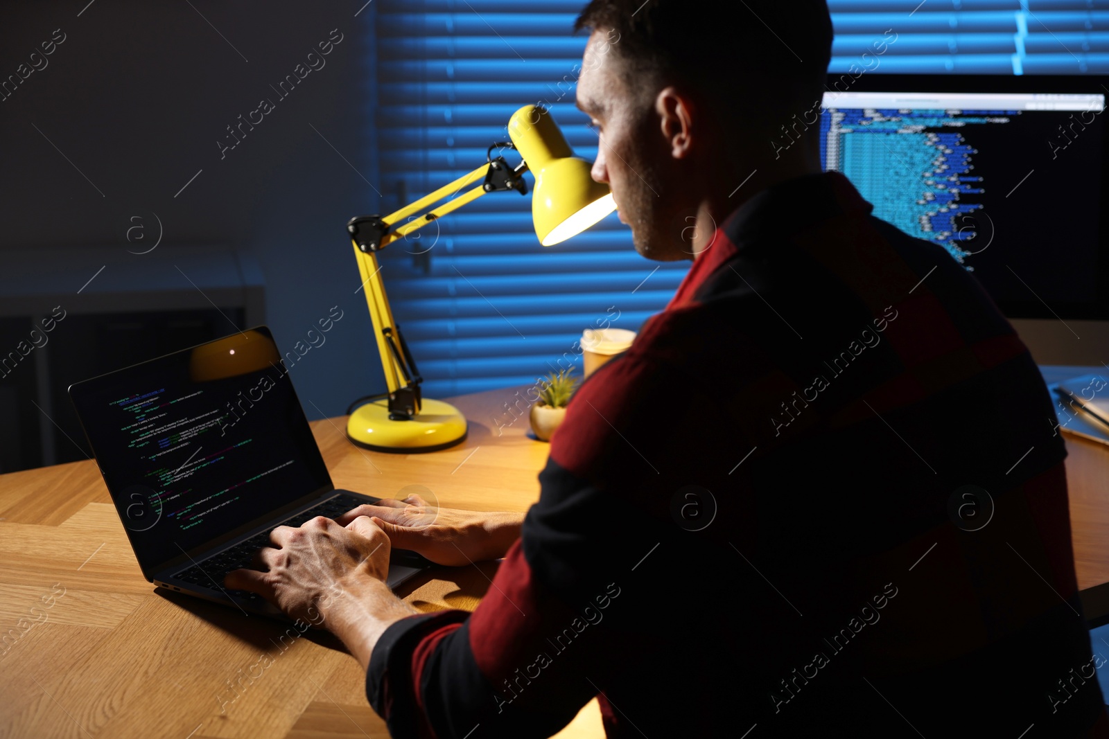 Photo of Programmer working on laptop indoors at night