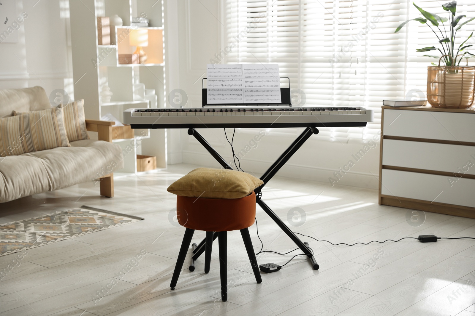 Photo of Synthesizer with music sheets, pouf and pillow indoors