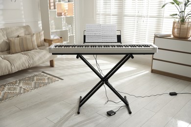 Photo of Synthesizer with music sheets indoors. Electronic musical instrument