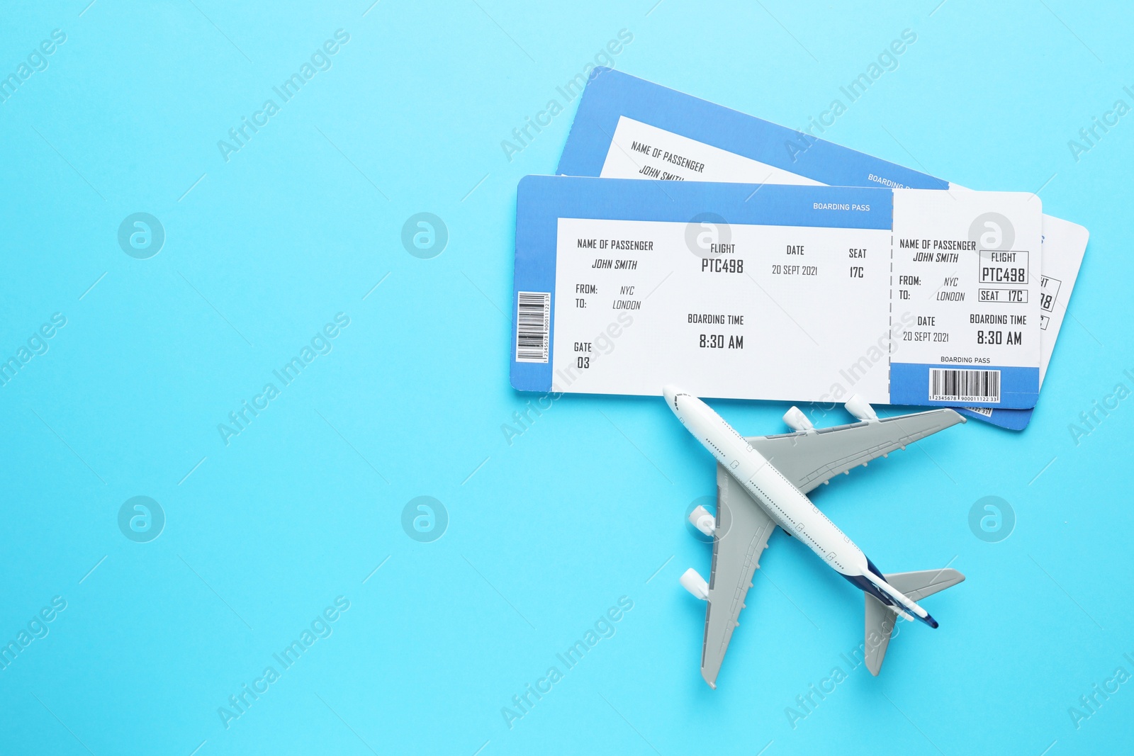 Photo of Travel agency. Flight tickets and plane model on light blue background, flat lay. Space for text