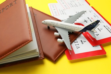 Photo of Travel agency. Flight tickets, passports and plane model on yellow background, closeup