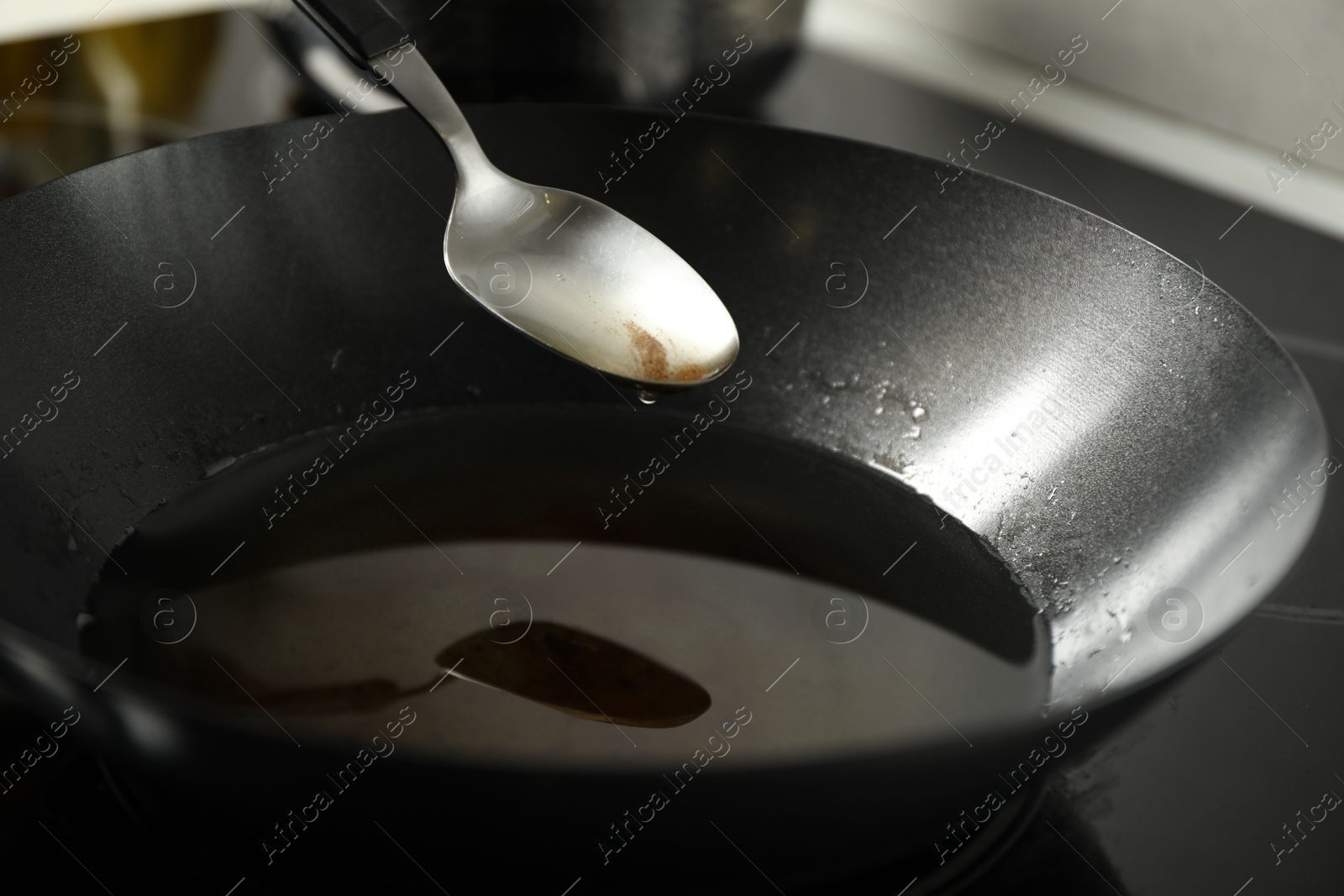 Photo of Used cooking oil in frying pan and spoon at stove, closeup