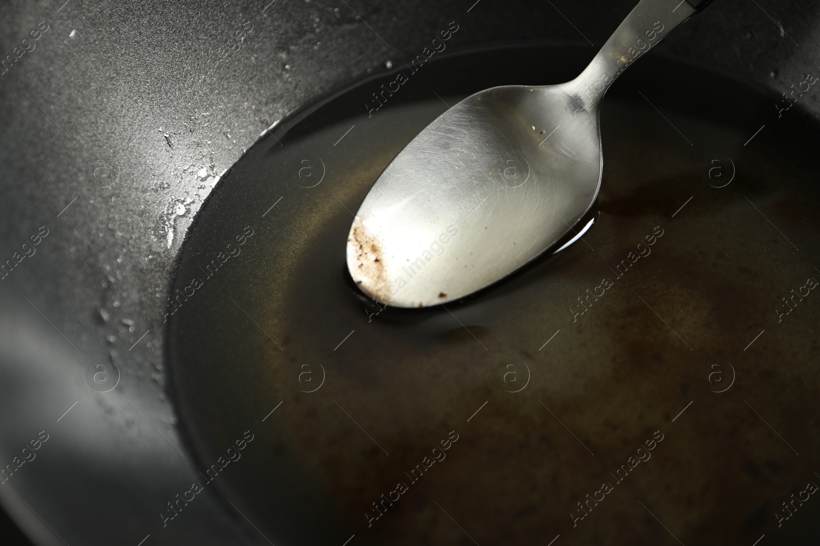 Photo of Used cooking oil and spoon in frying pan, closeup