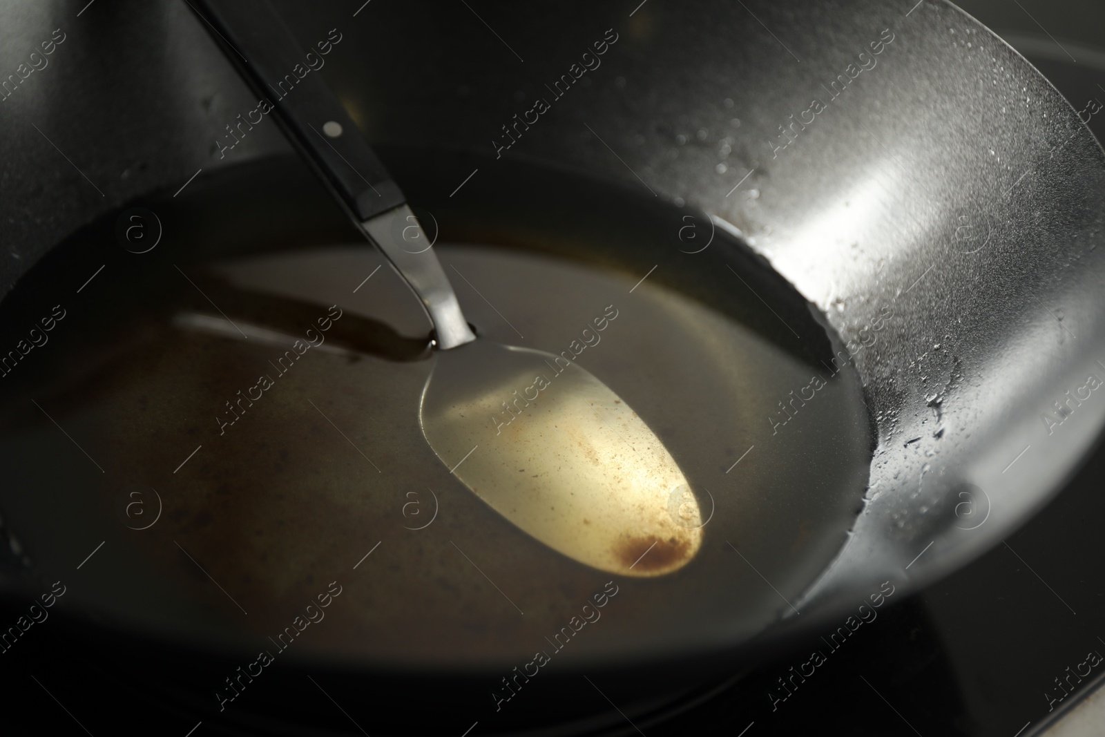 Photo of Used cooking oil and spoon in frying pan, closeup