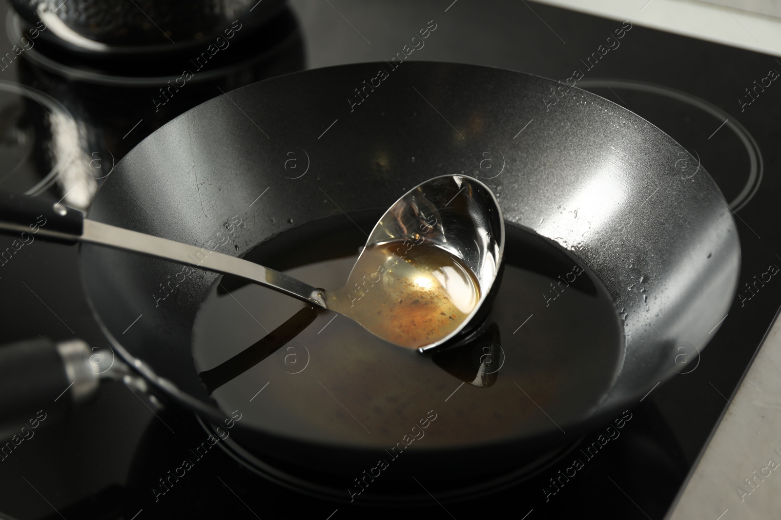 Photo of Used cooking oil and ladle in frying pan on stove, closeup