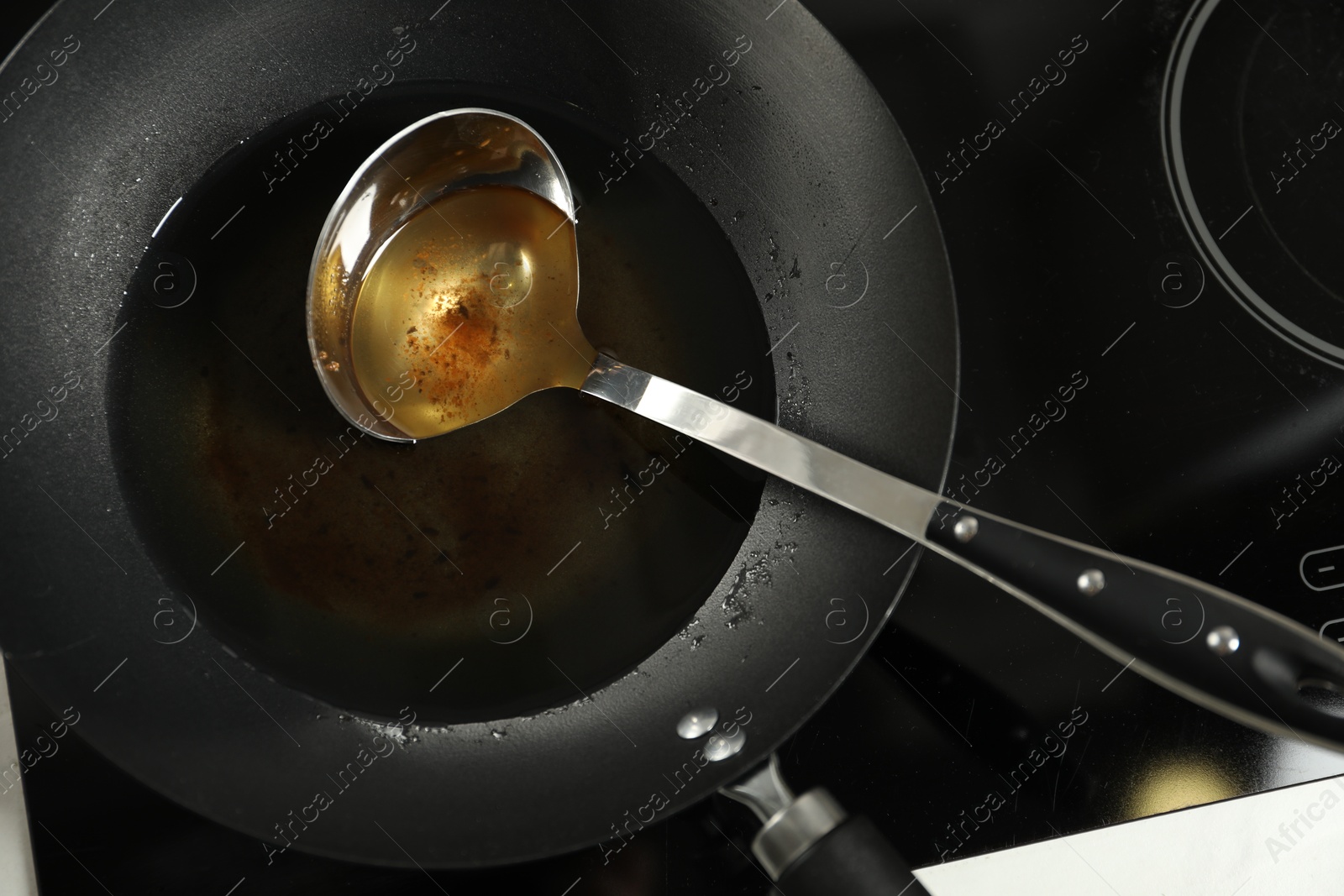 Photo of Used cooking oil and ladle in frying pan on stove, above view